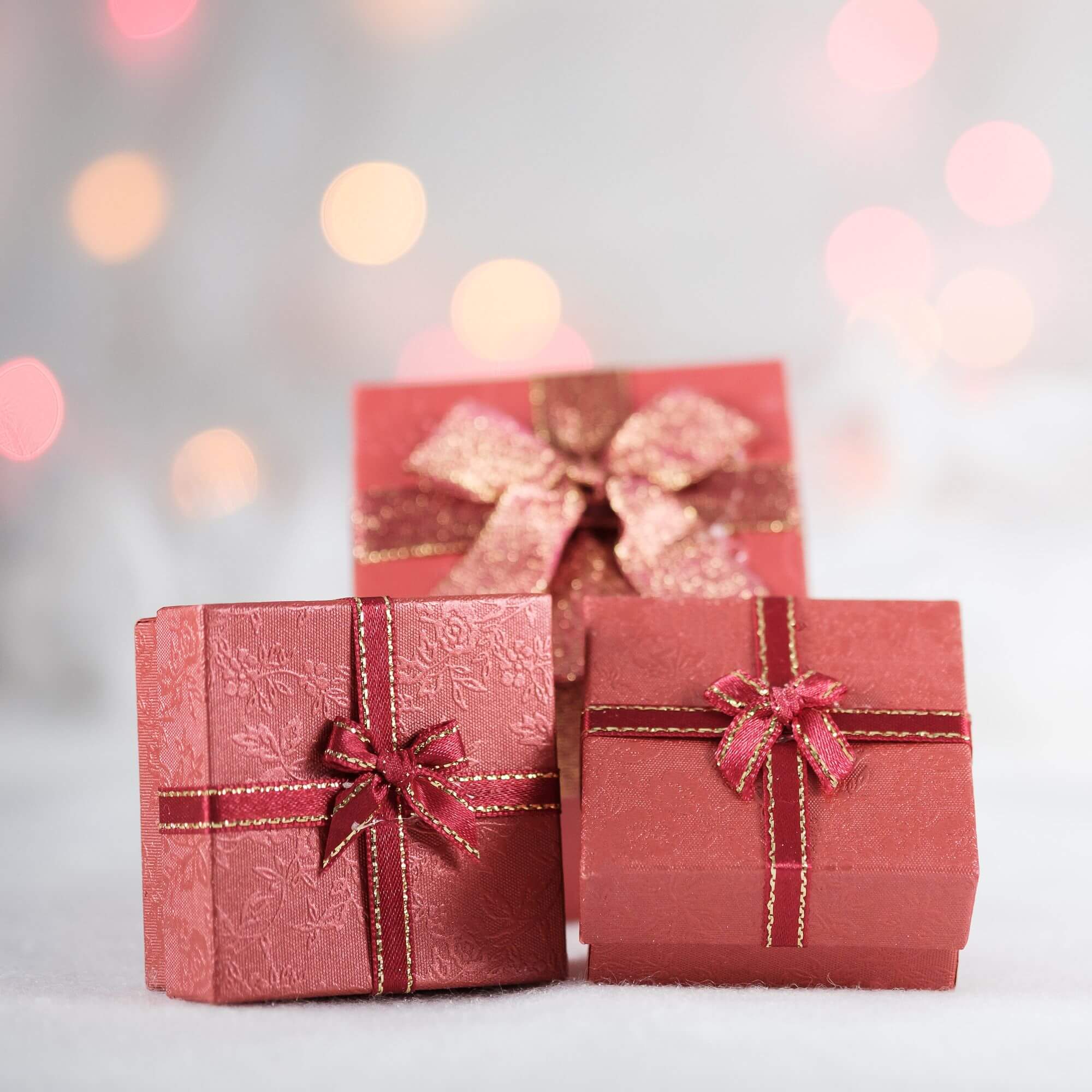 Three Christmas presents wrapped in red boxes and red ribbon