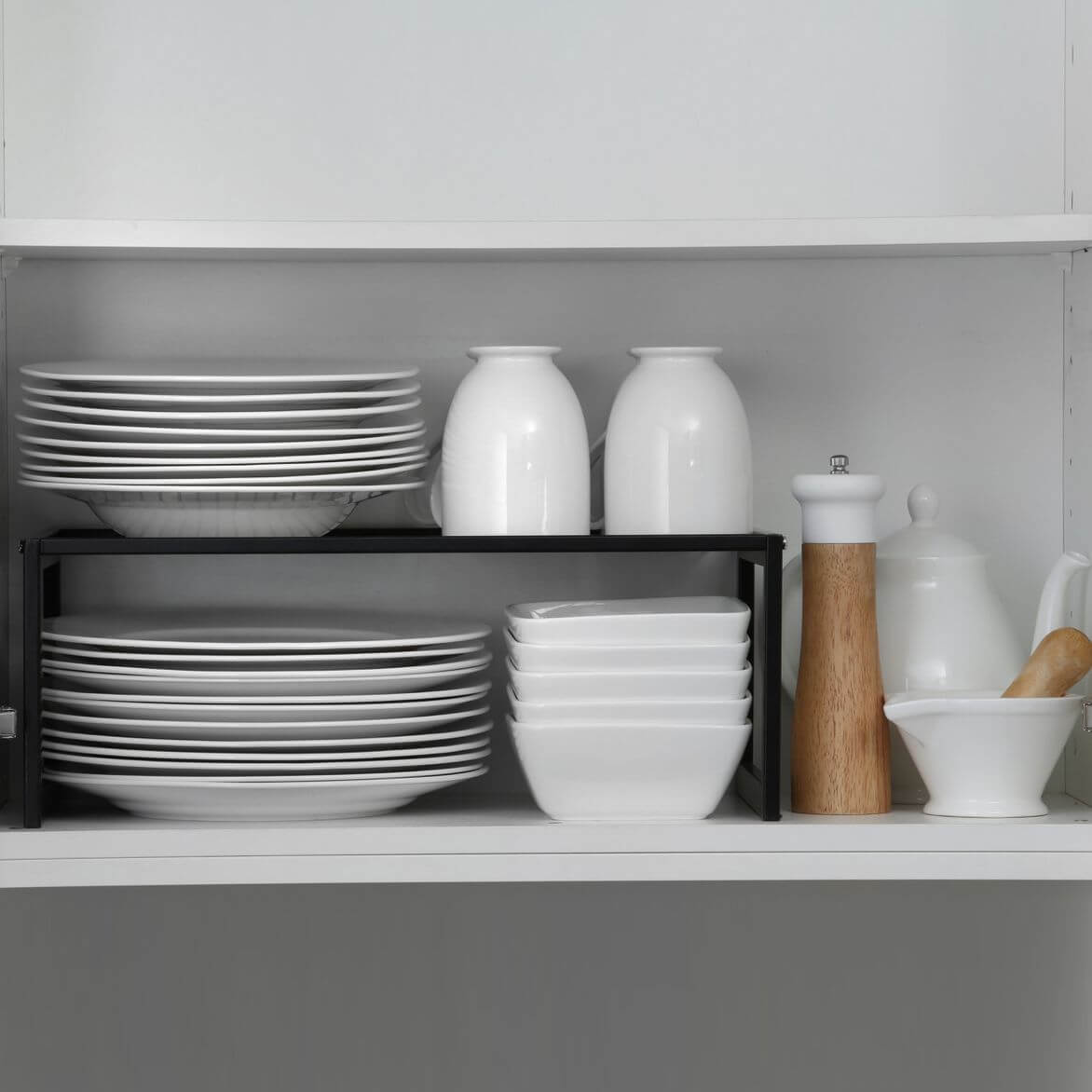 Kitchen plates and bowls on a matte black stackable pantry shelf