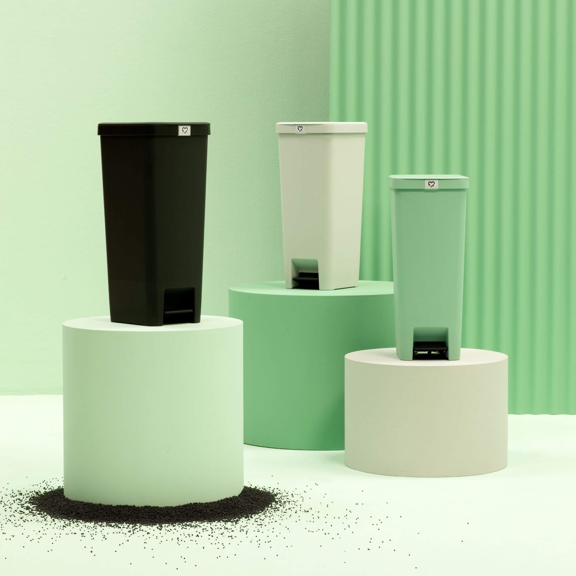 Dark Grey, Light Grey and Jade Green StepUp kitchen bins standing on three raised bases.