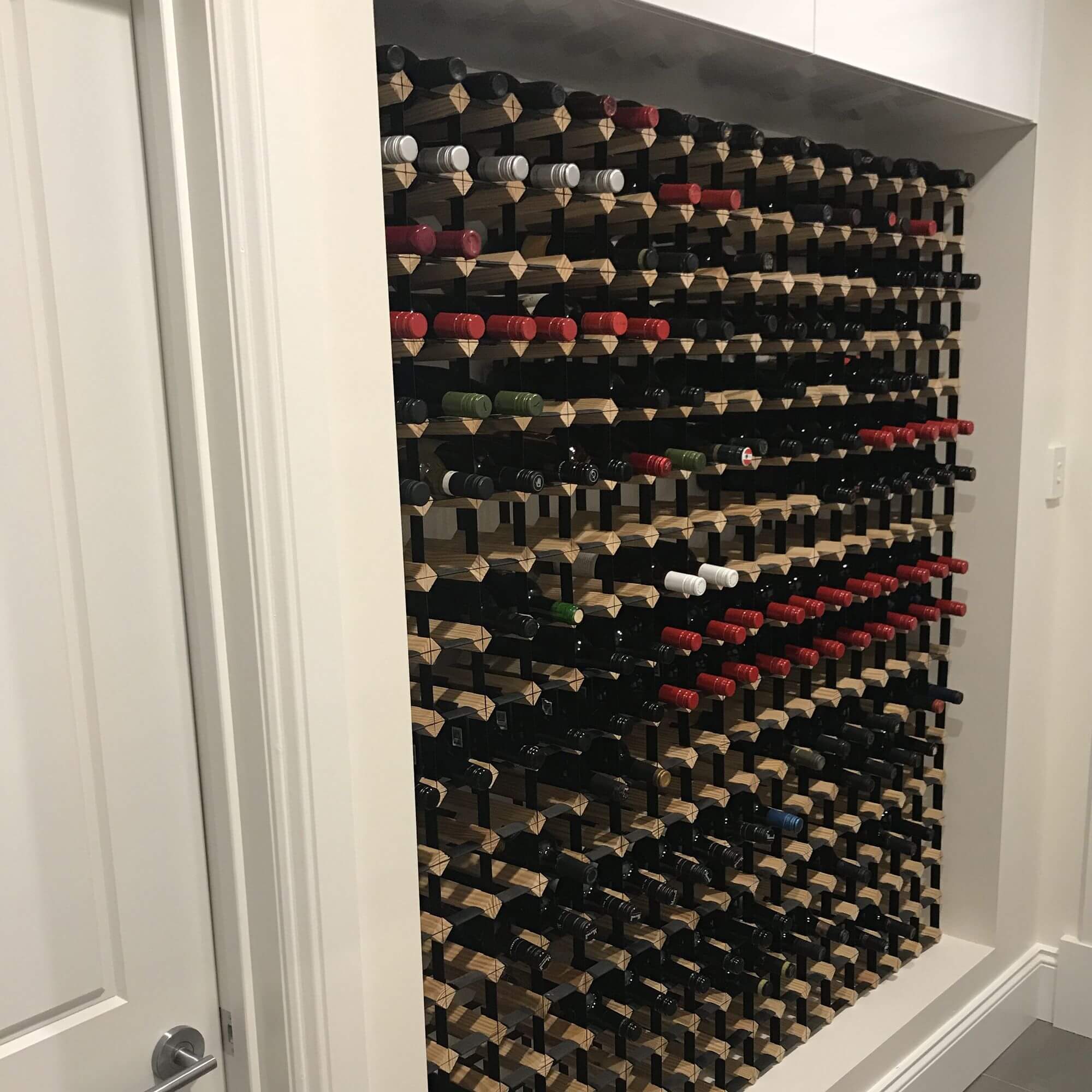 Timber and metal wine rack storing many bottles of wine in a home