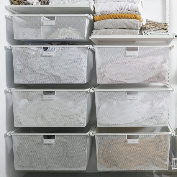 Seven White Elfa Gliding Mesh Drawers installed in a laundry for sorting clothes and washing