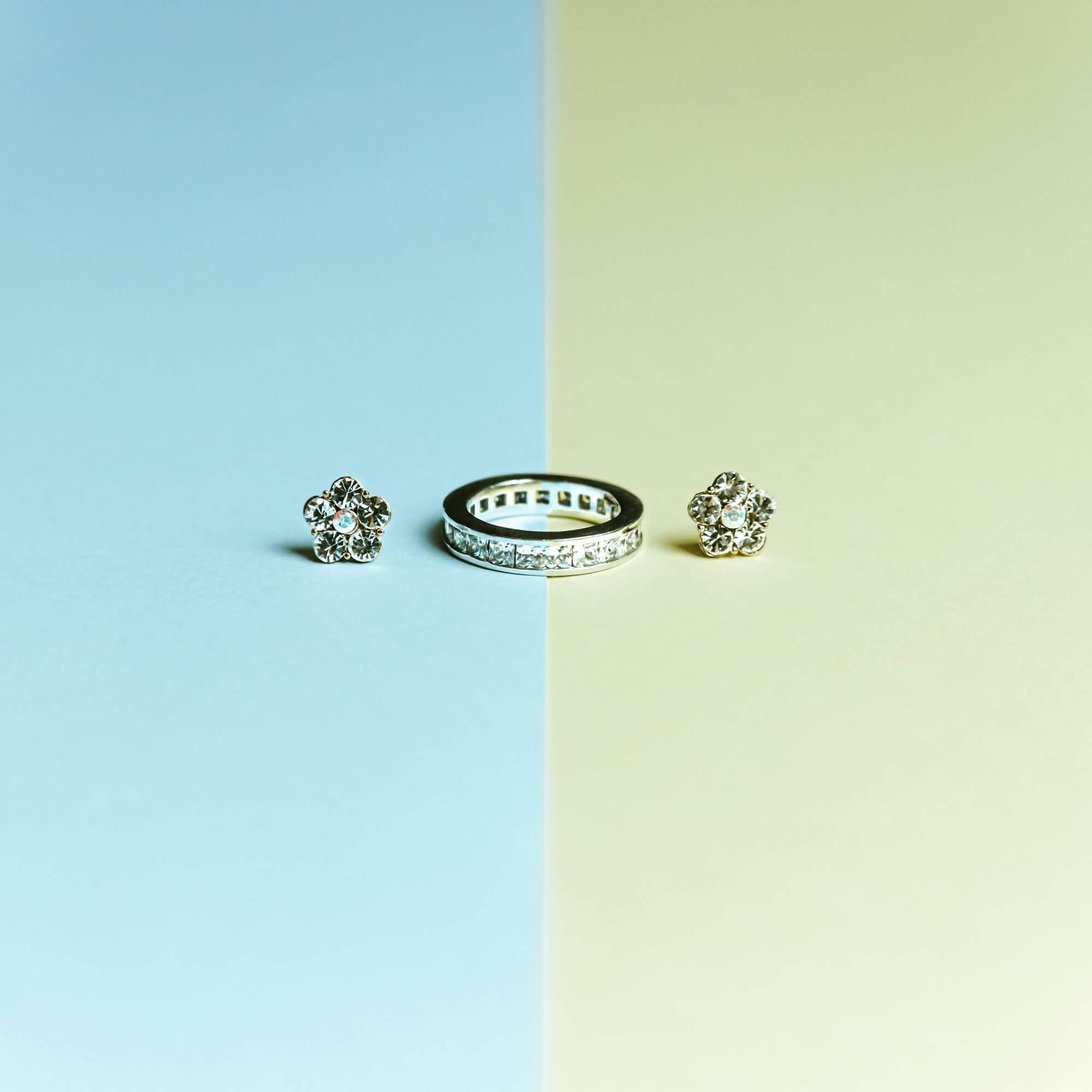 Silver earrings and a ring stored on a blue and green shelf