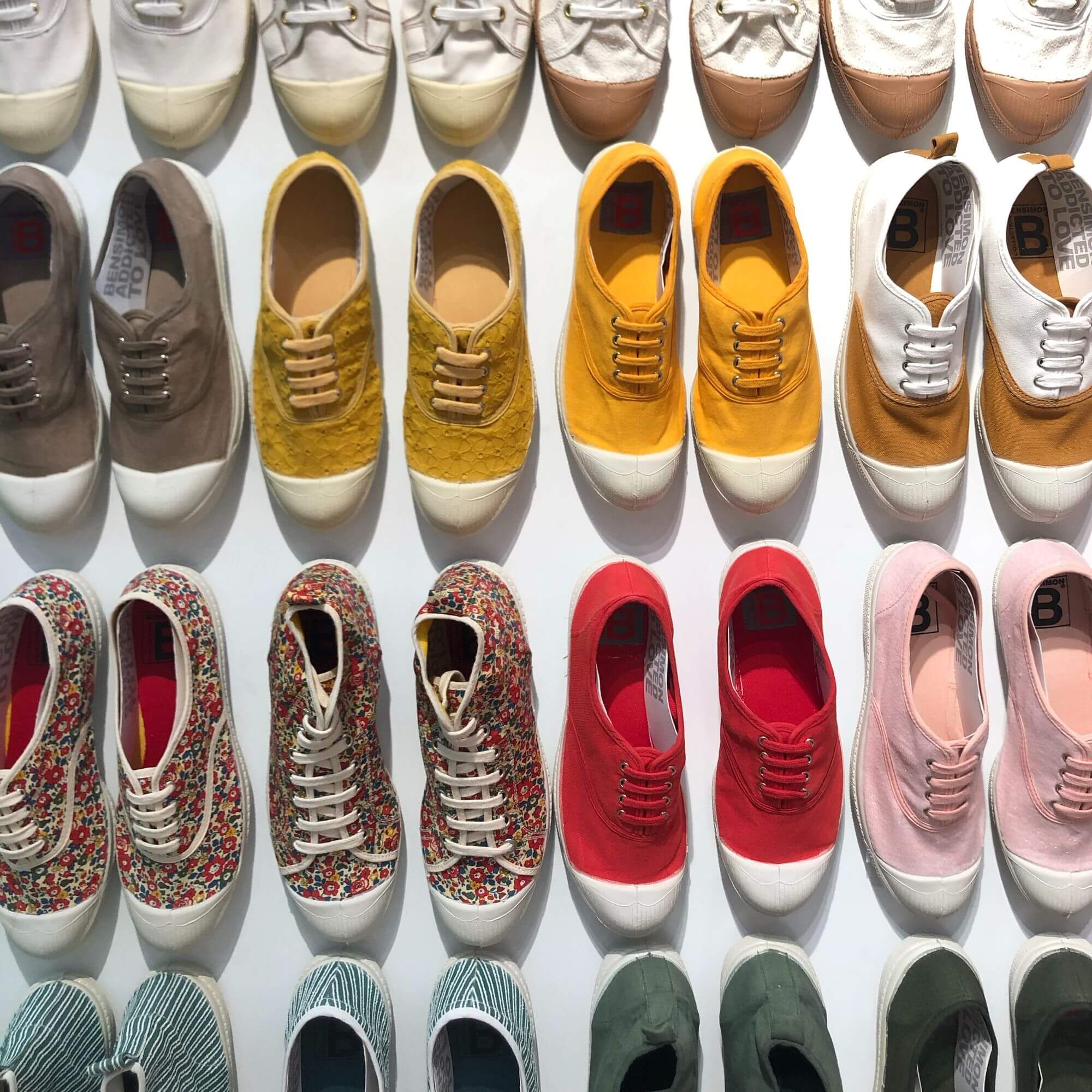 Colourful shoes lined up in four rows on a white background