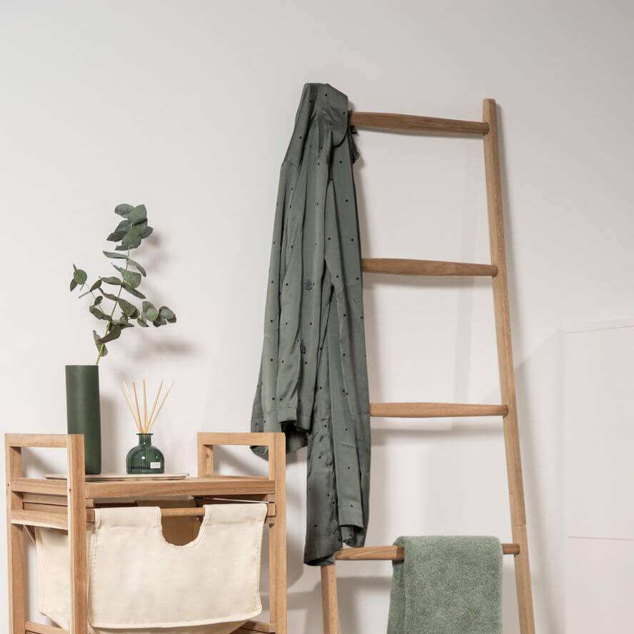 Timber towel storage ladder with grey clothes hanging up