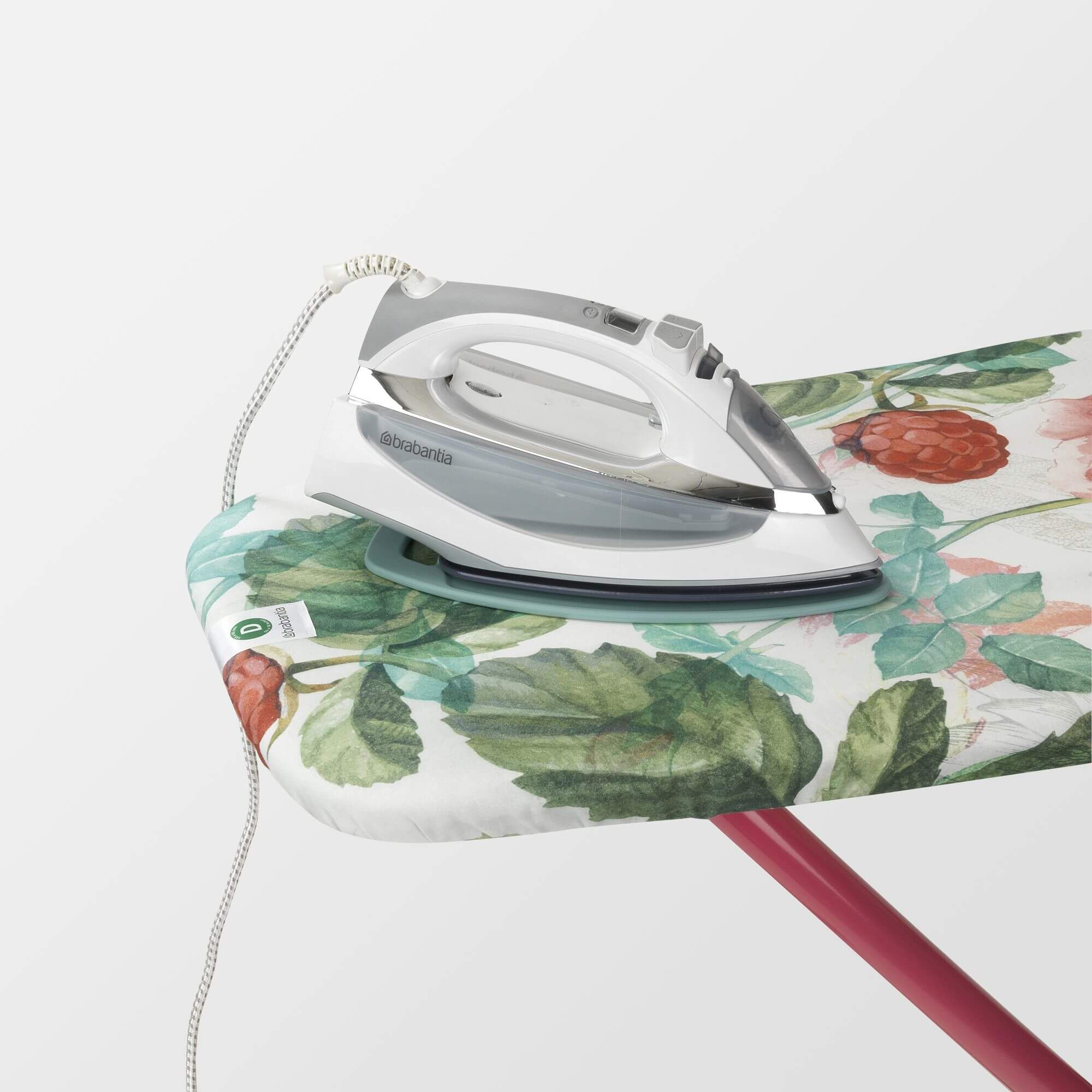 An iron sitting on top of a floral Brabantia ironing board cover