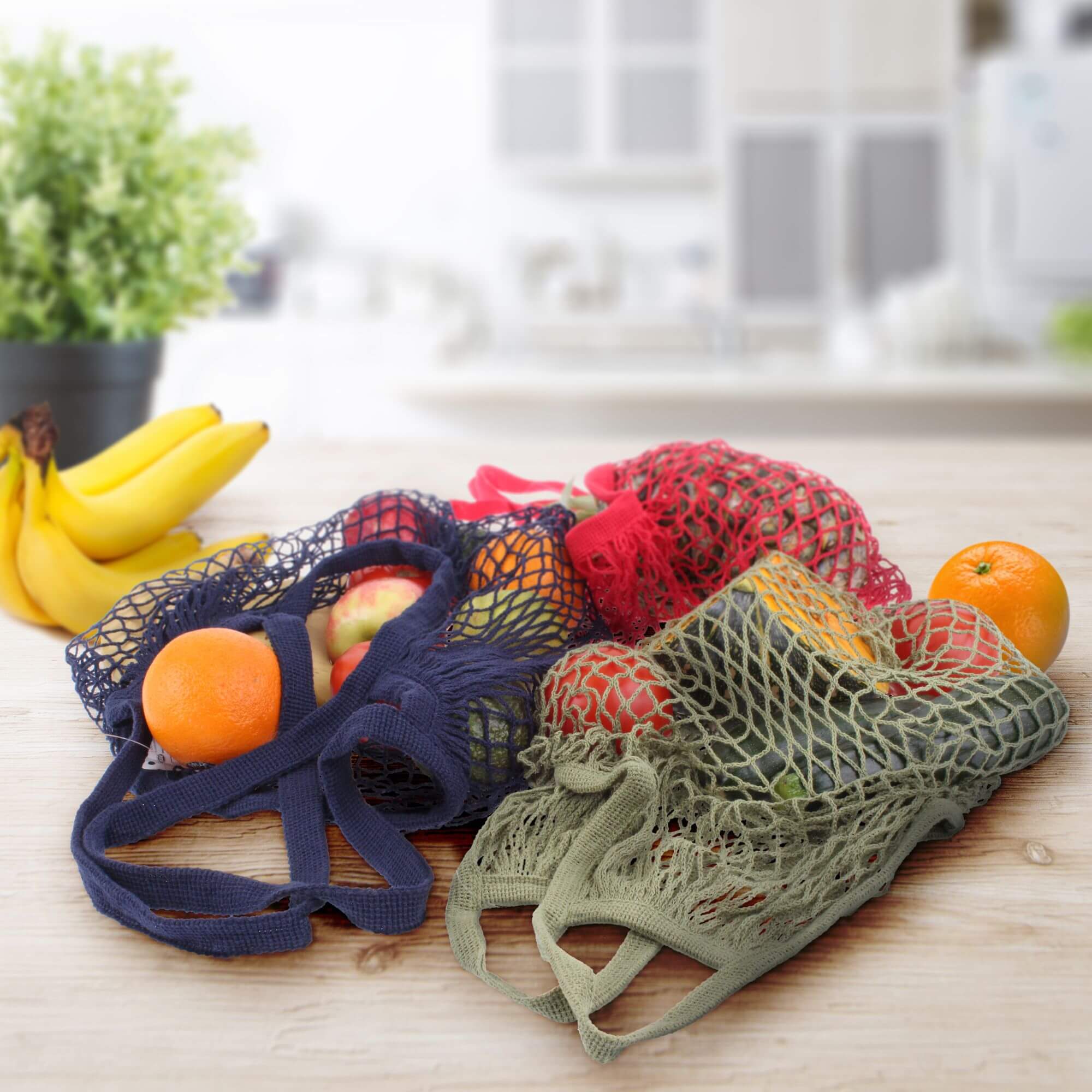 Reusable shopping bags on a kitchen bench with groceries inside