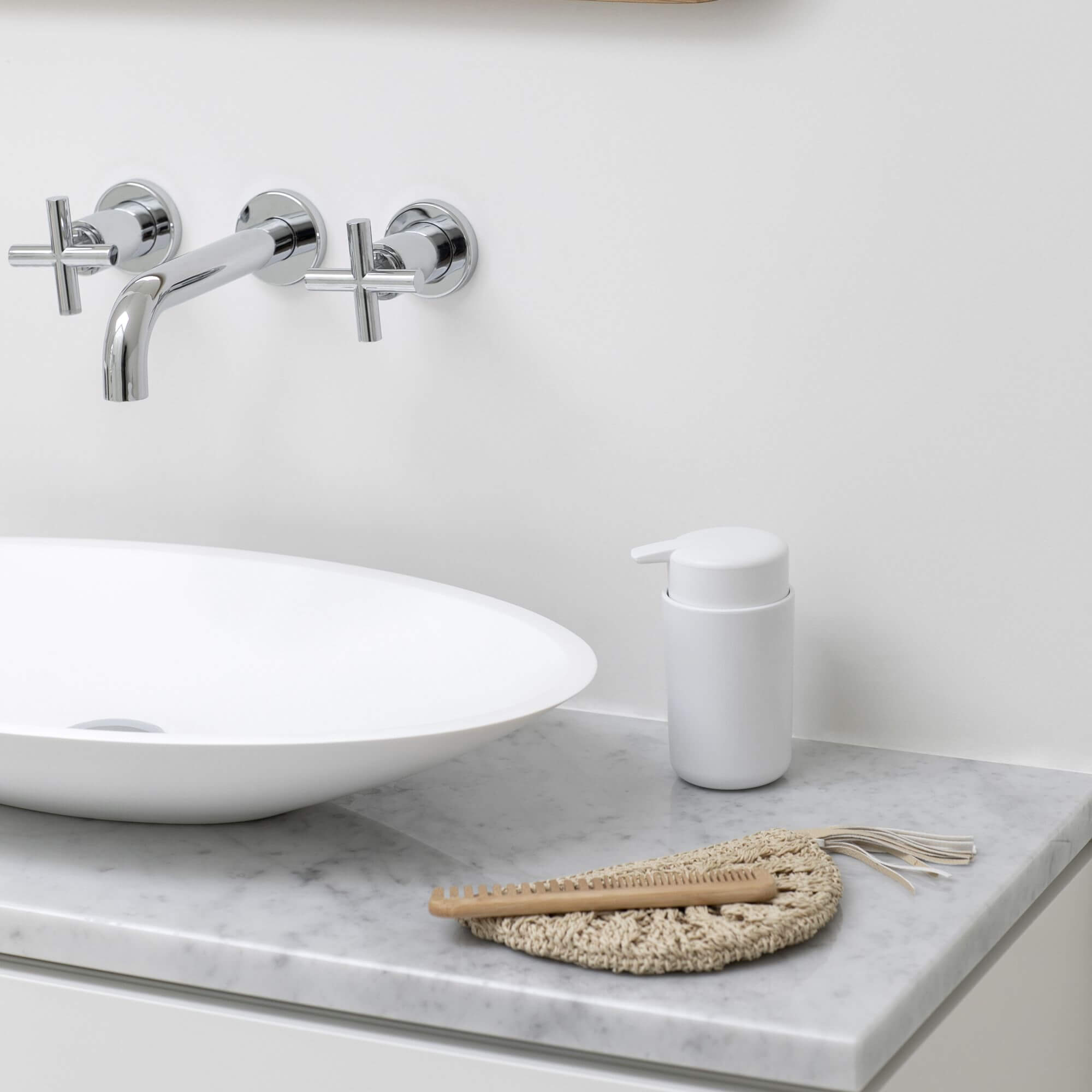 White Brabantia soap dispenser next to a sink on a bathroom vanity