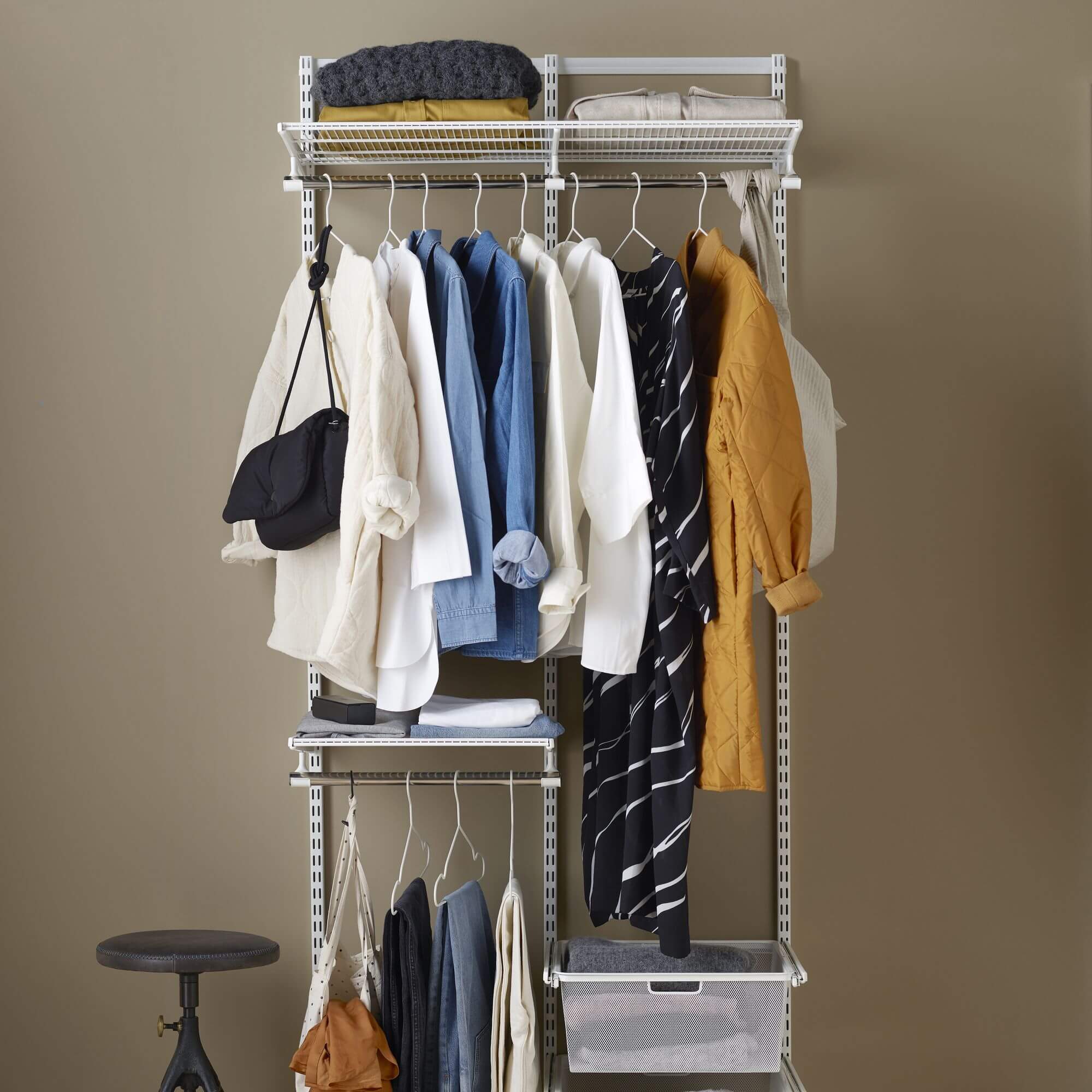 A white Elfa wardrobe shelving system with shelves, hanging rail and gliding drawer