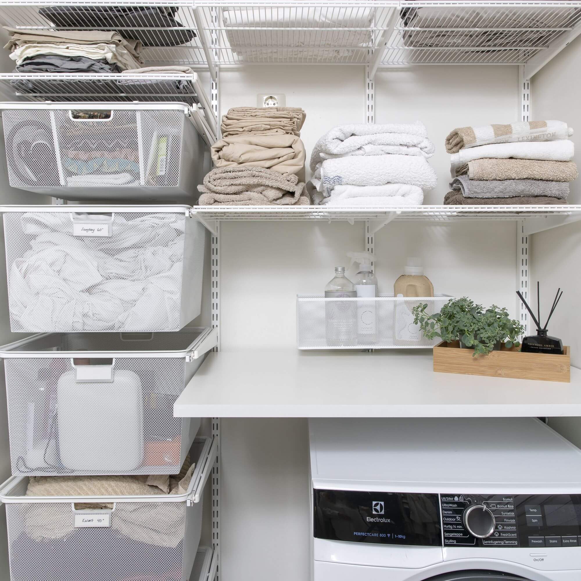 An Elfa laundry shelving system with dirty laundry storage, folded linen and cleaning products