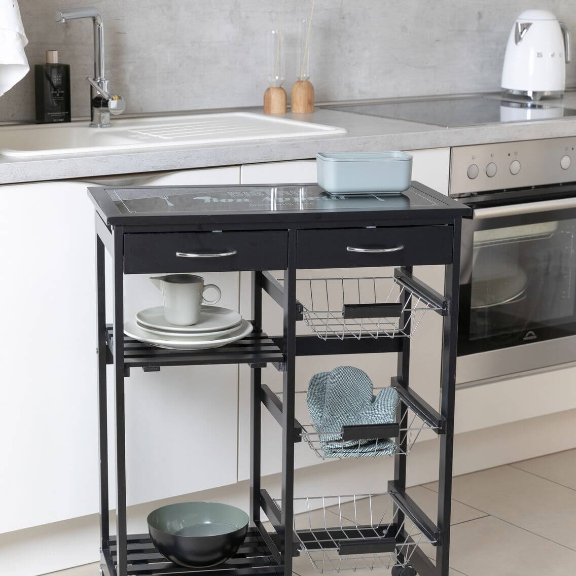 A black kitchen storage trolley standing in front of a kitchen cupboard