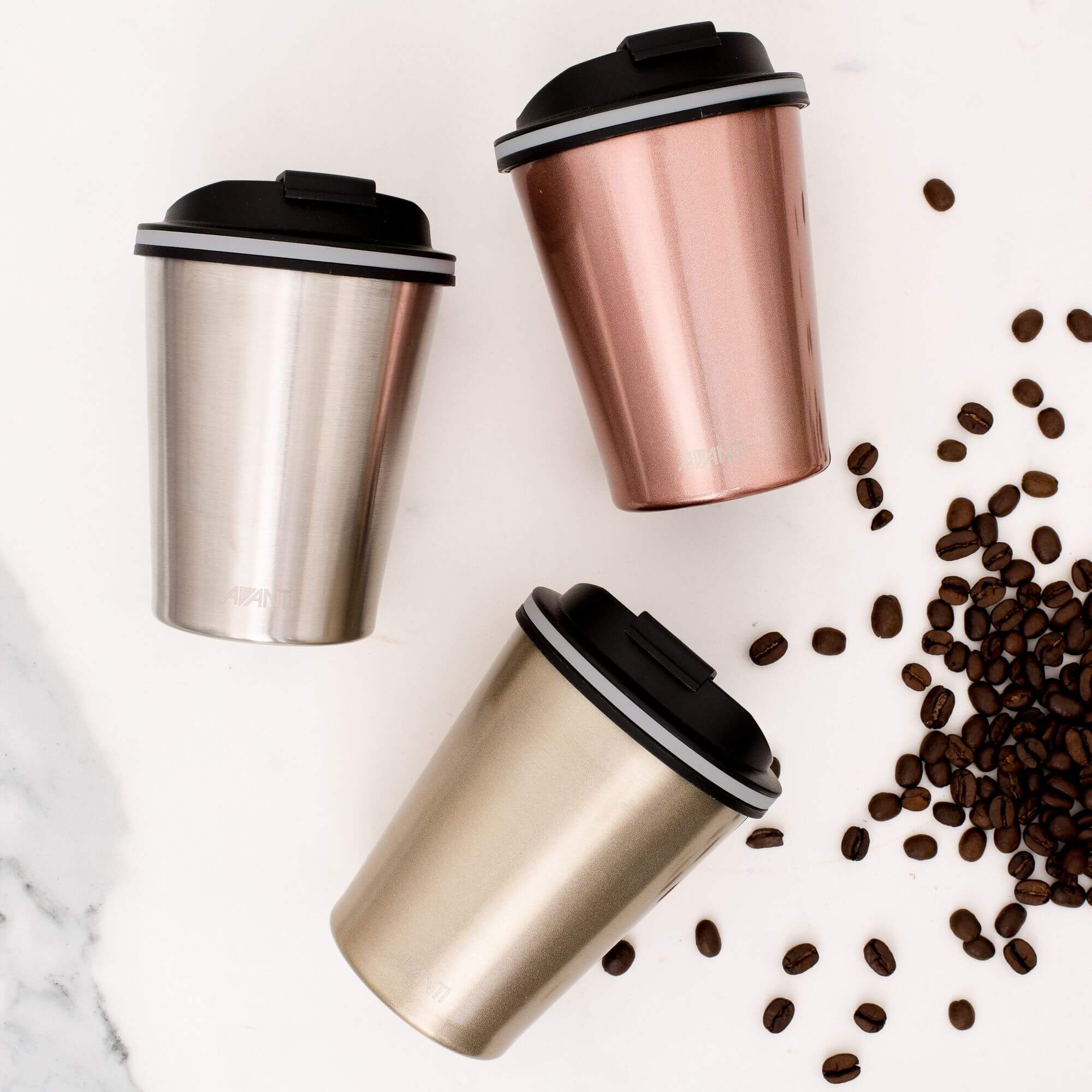 Insulated stainless steel coffee cups next to coffee beans