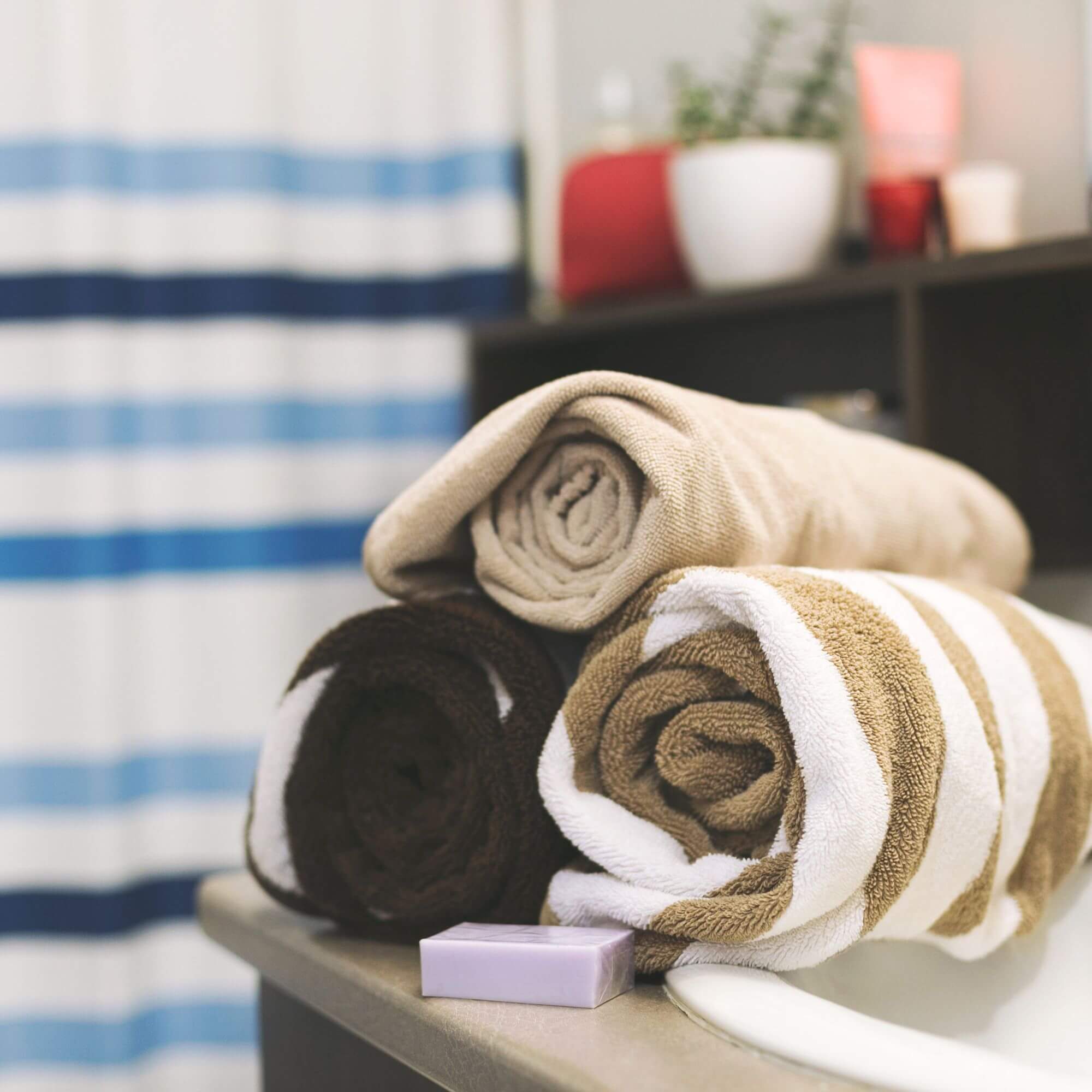Three striped guest towels sit on a bathroom vanity with a bar of purple soap.