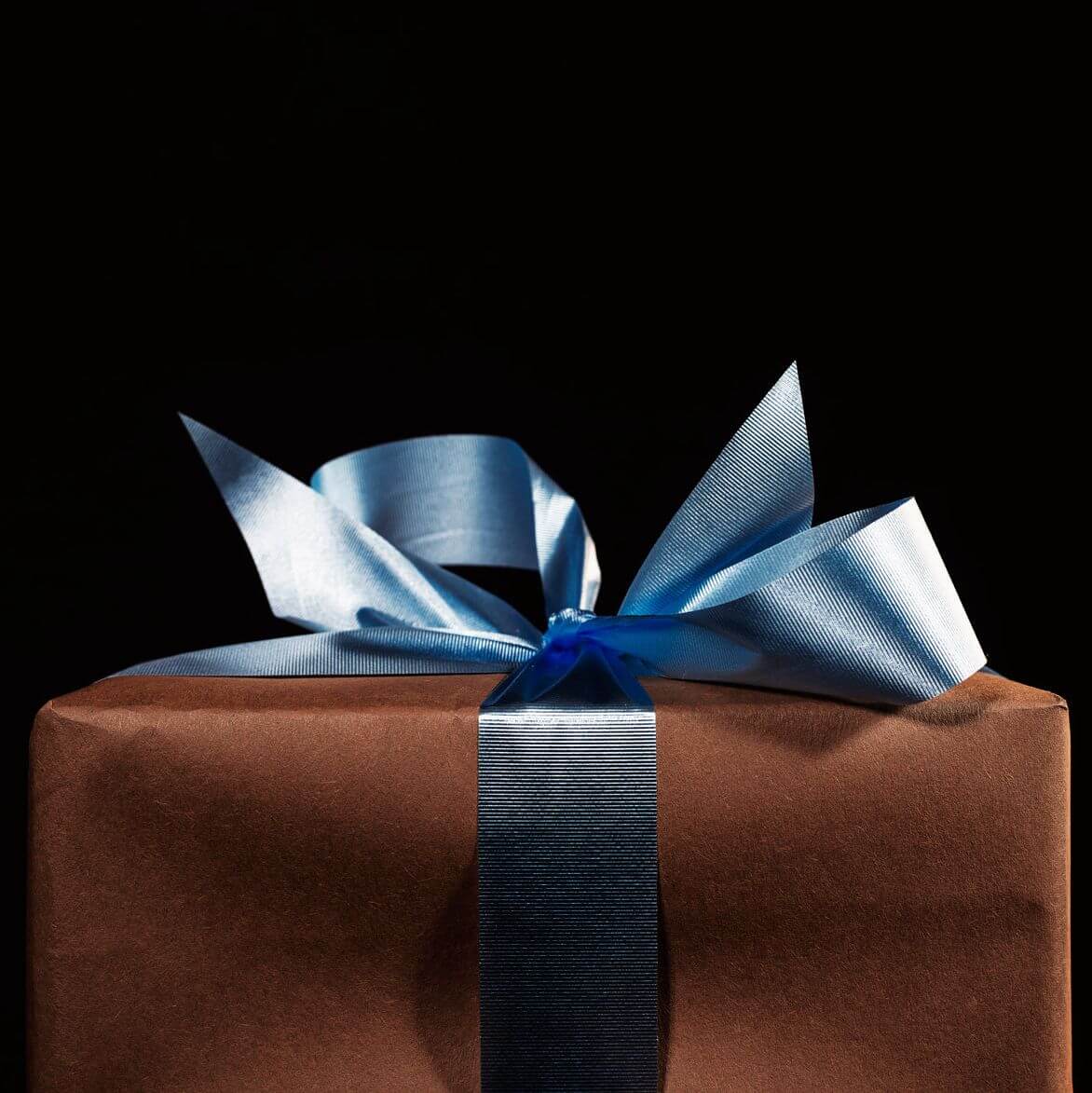 A Christmas or birthday present with brown wrapping paper and a blue ribbon