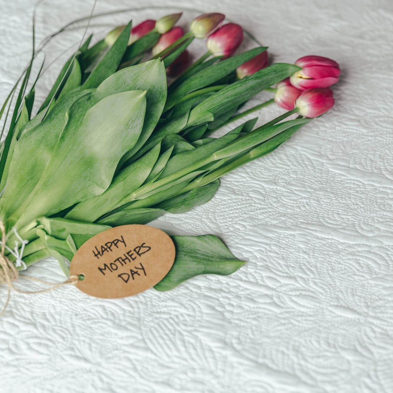 A gift tag saying "Happy Mothers Day" on top of a bunch of flowers