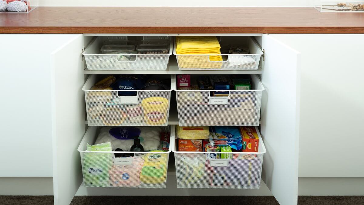 Six White Elfa Easy Gliders installed in a kitchen cupboard, with food containers, kitchen roll and pantry supplies stored inside