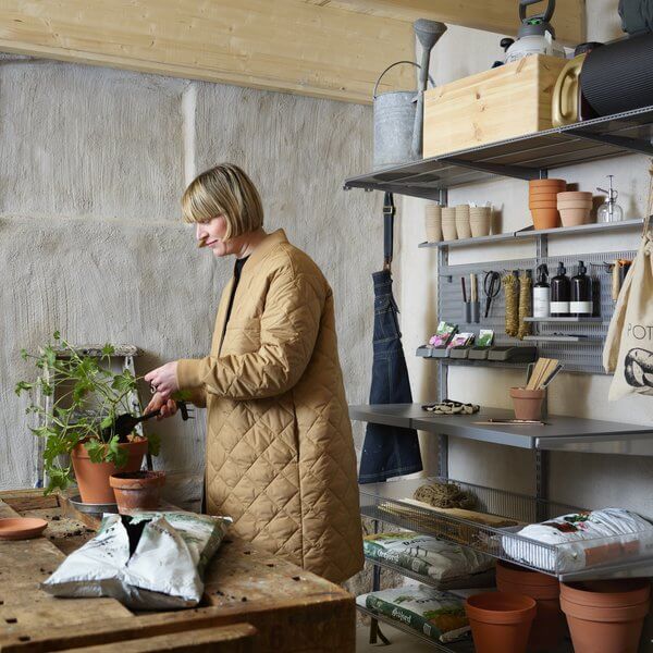 A woman potting plants with gardening equipment stored on a Platinum Elfa system