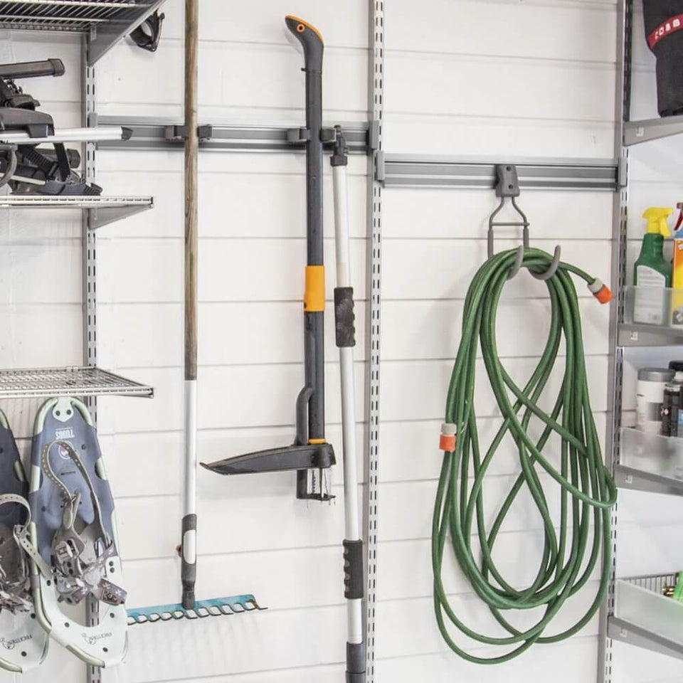 A Rake and garden hose stored on a Platinum Elfa Storage Track in a garage
