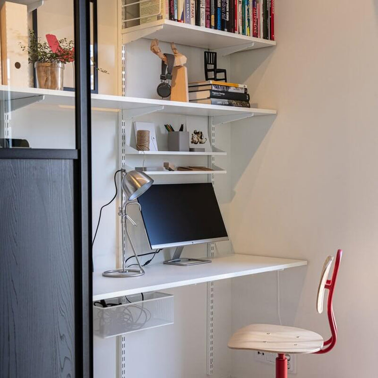 White Elfa shelves used as a wall-mounted office desk and bookshelves
