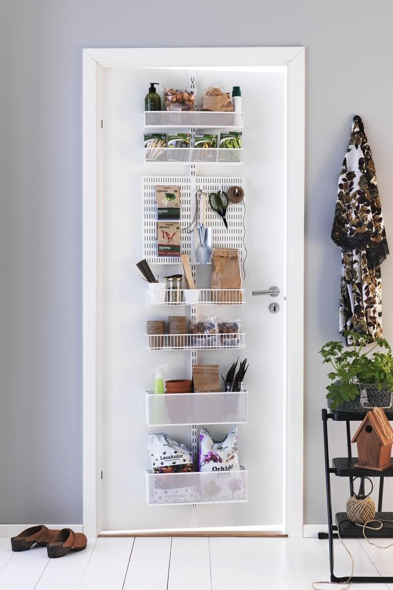 A White Elfa Utility Wall & Door system with Mesh Utility Baskets and a Centre Storing Board, used for over-the-door storage of kitchen, gardening and home supplies