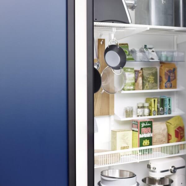 A White Elfa pantry, with Wire Shelf Baskets, Reversible Metal Trays and Shelf Hooks all used to organise the pantry contents