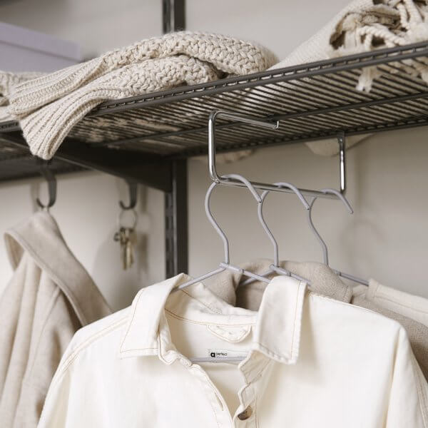 A chrome Elfa Valet Rod hanging clothing front-facing in a wardrobe