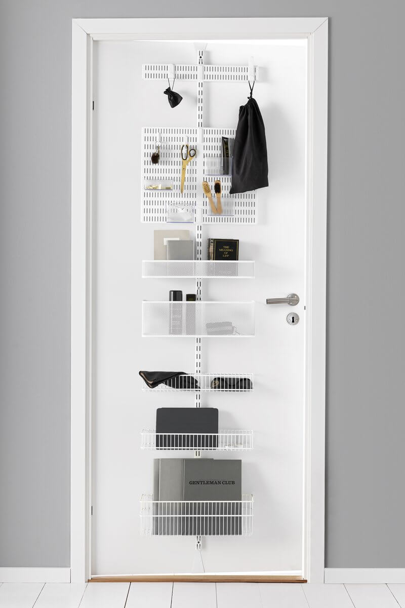 A White Elfa Utility Wall & Door system with Mesh and Wire Utility Baskets and a Centre Storing Board, used for over-the-door storage of books, bags and stationery